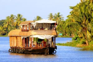 Under the coconut trees, a rice houseboat in the Kerala water canal