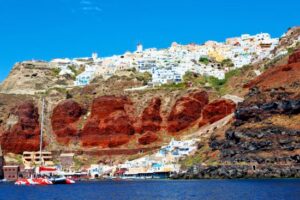 Greece tour: Santorini’s towering volcanic caldera walls showcase Red and Black Lava Cliffs.